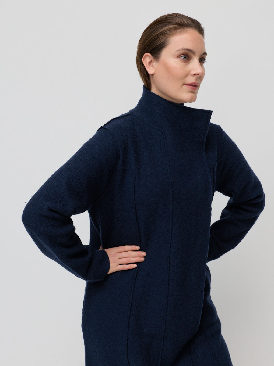 Woman wearing a navy blue coat against a light gray background