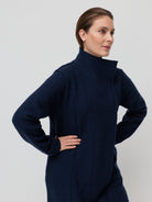 Woman wearing a navy blue coat against a light gray background