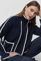 Woman wearing a navy cardigan with white trim against a plain background