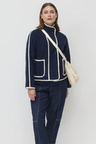 Woman wearing a navy blue outfit with white accents on a plain background