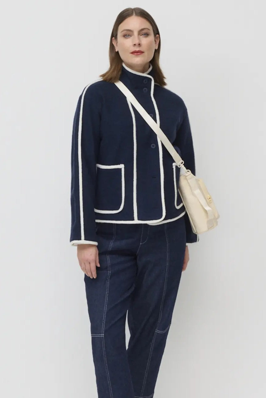 Woman wearing a navy blue outfit with white accents on a plain background