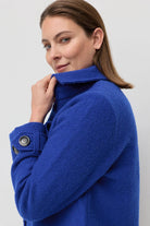 Woman wearing a blue coat against a plain background