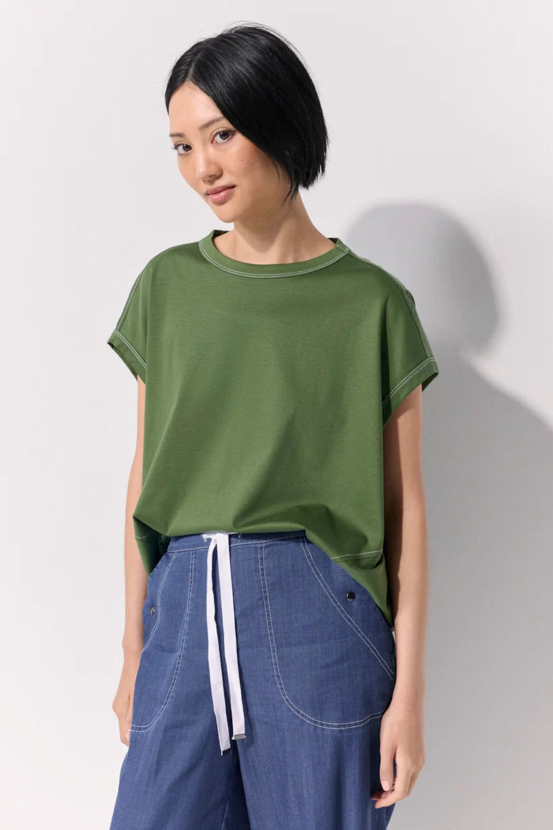 Woman wearing a green tee shirt and wide leg 7/8 light denim pants with contrast top stitching and pockets against a white background.