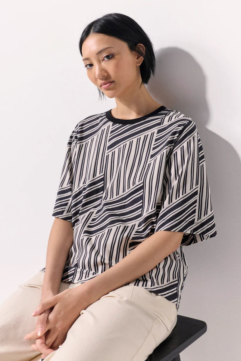 A woman wearing an abstract design black and white tee shirt against a white background.
