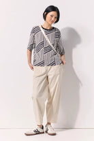 A woman wearing an abstract design black and white tee shirt against a white background.