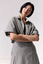 A woman wearing a pleated striped midi skirt and matching top against a white background.