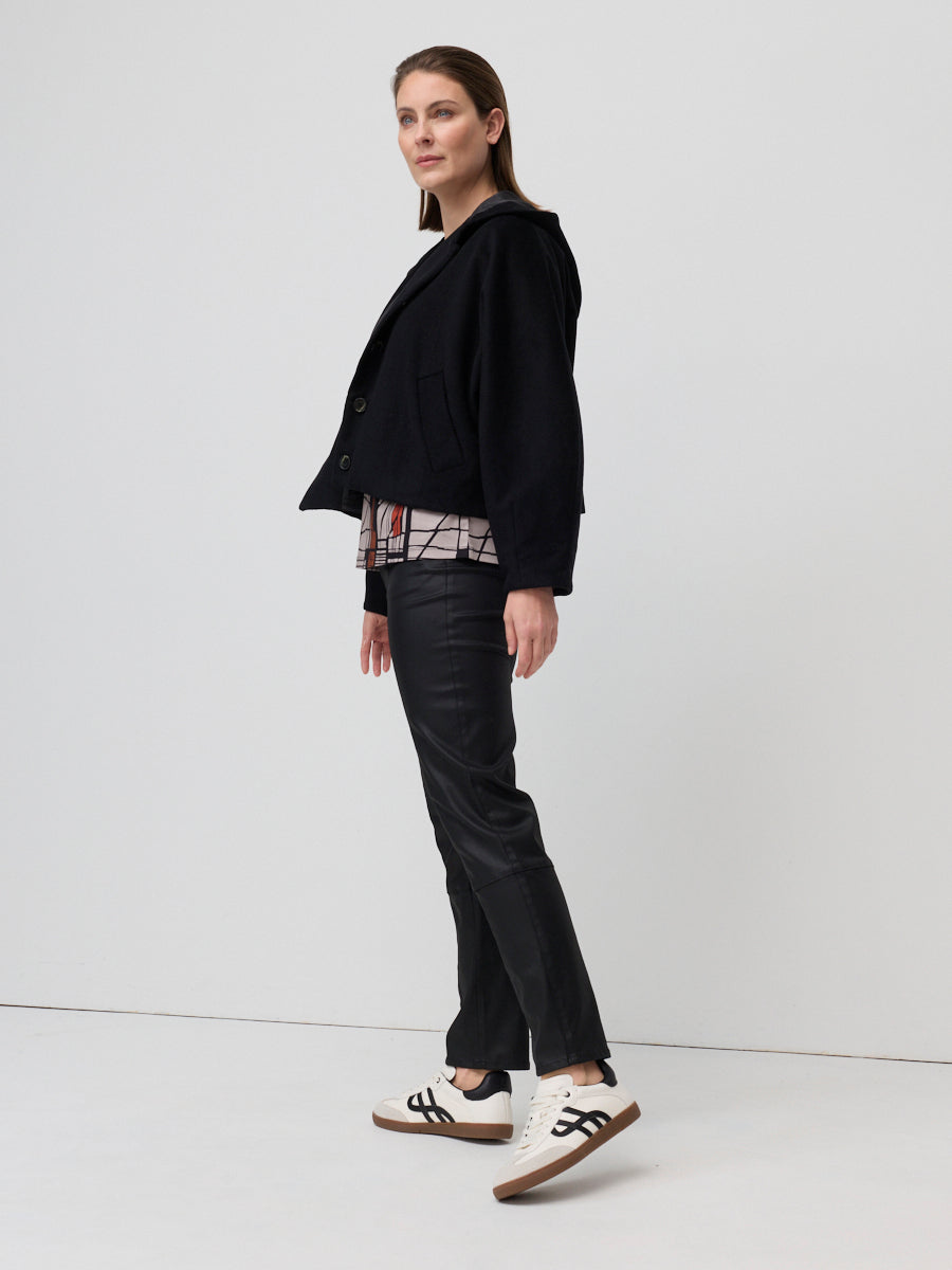Woman wearing a black jacket and black pants on a white background