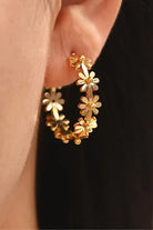 Gold hoop earrings with floral designs on ear