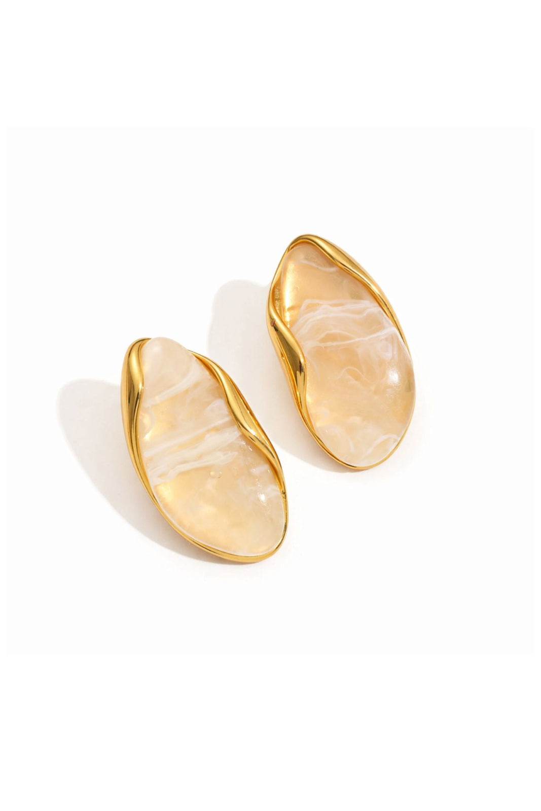 A pair of gold-toned oval stud earrings with smooth, organic-shaped cream and white marbled inlay, shown on a clean white background.