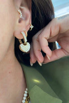 gold heart charm hoop earrings with pearl details on ear