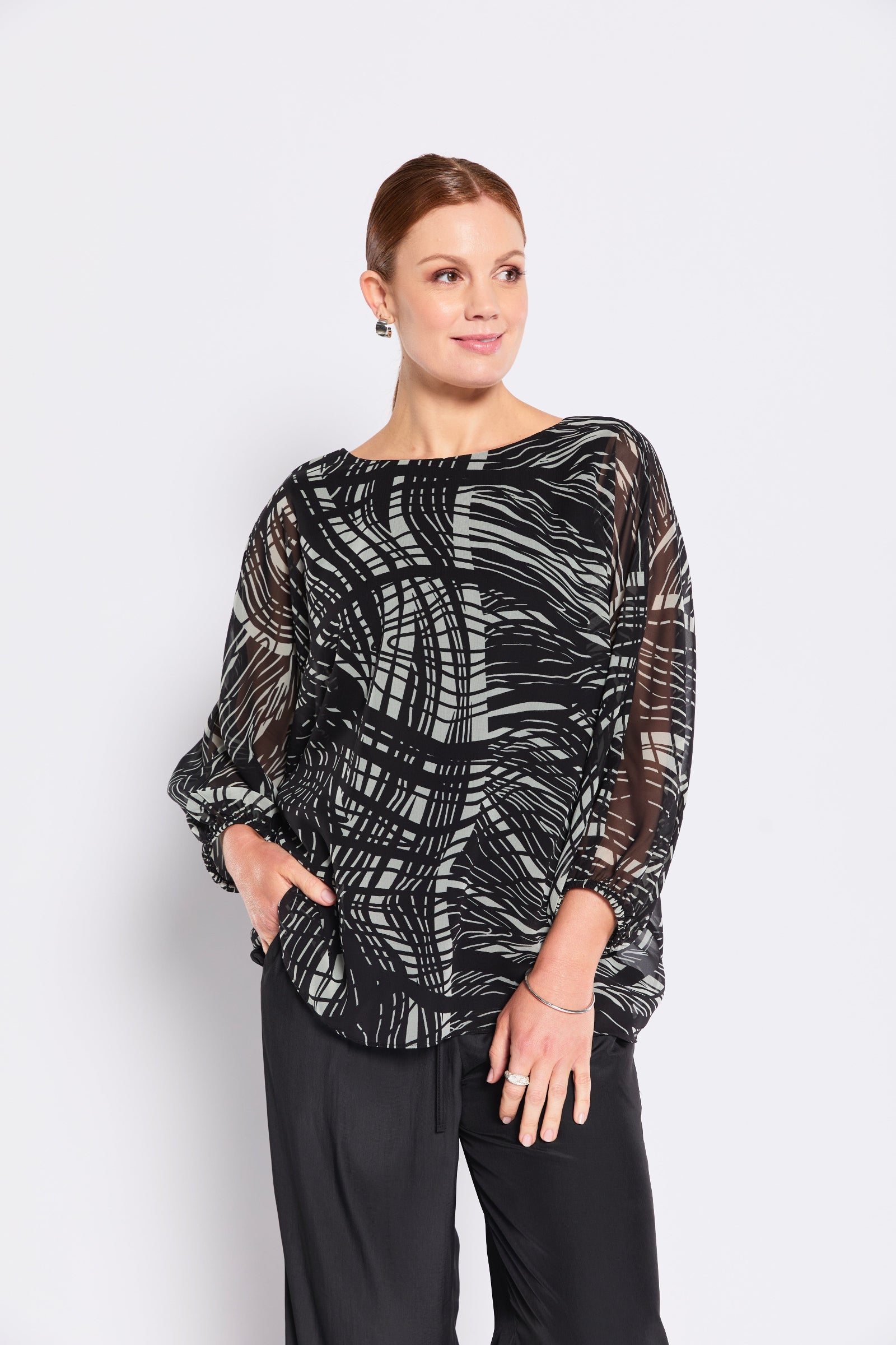 Woman wearing a black and sage patterned top on a white background