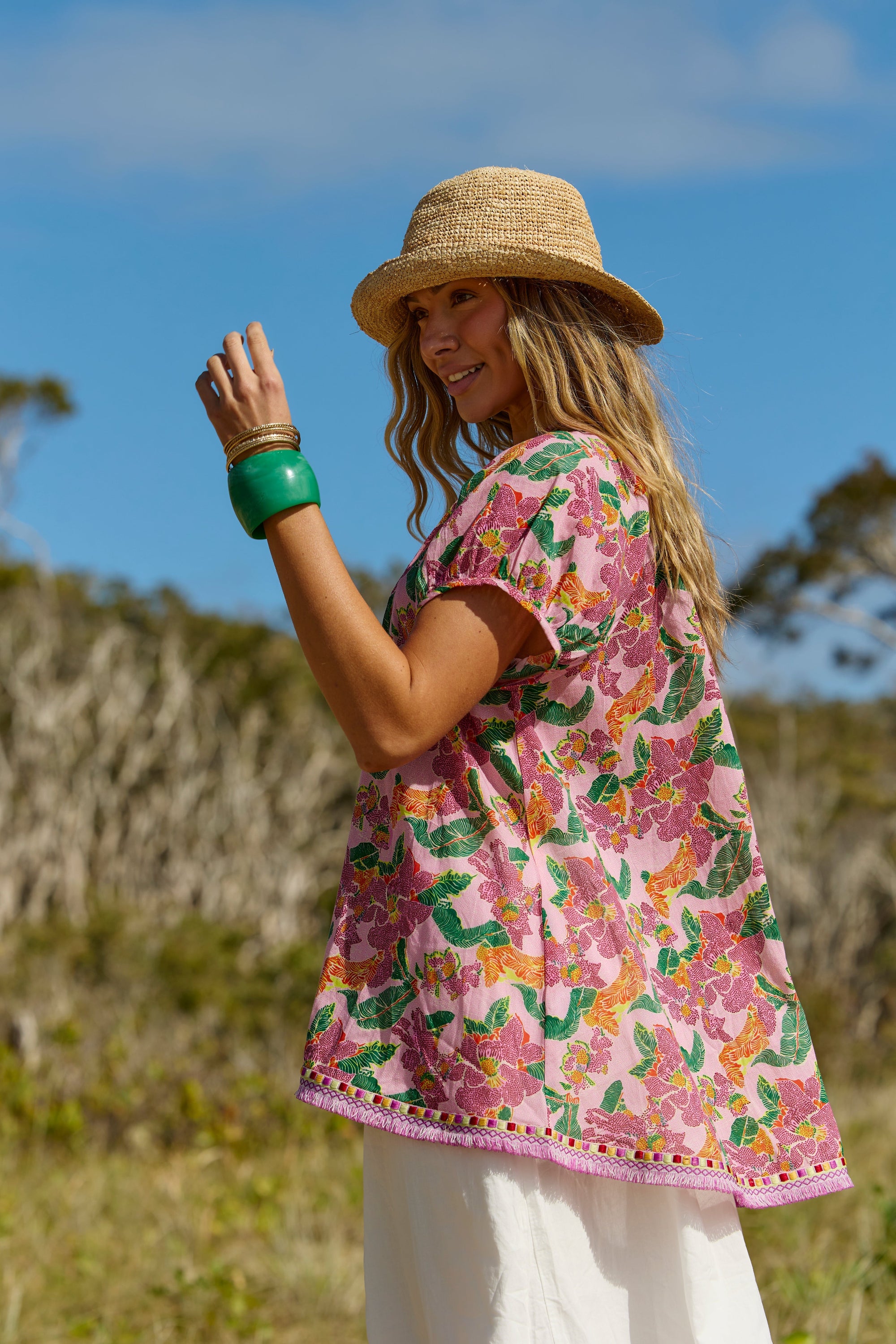 Woman wearing a floral pink cover-up and straw hat in a natural setting