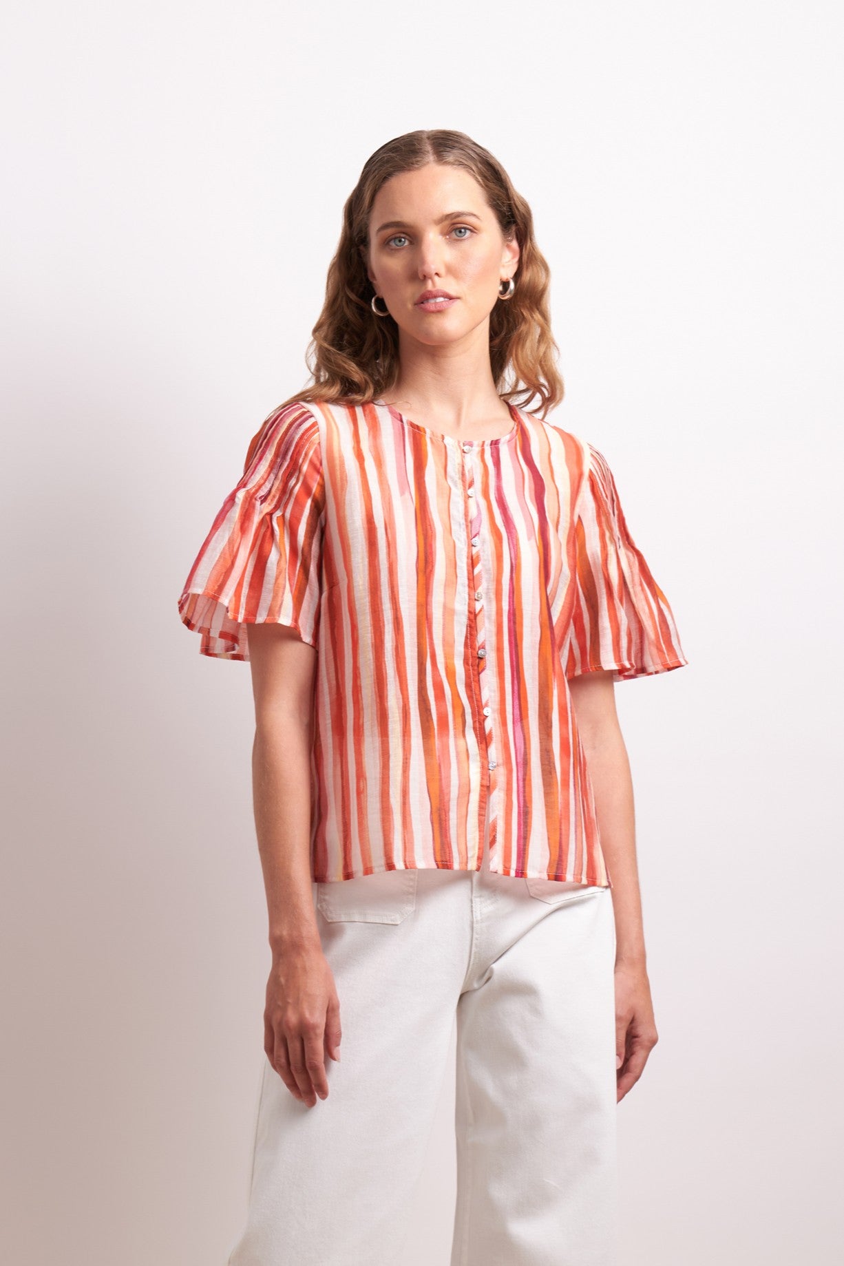 Woman wearing a striped orange and white blouse against a plain background