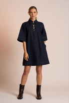 Woman wearing a navy dress with a beige background