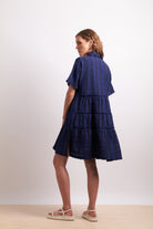 Woman wearing a blue tiered dress on a white background