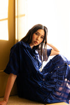 Woman in a blue dress sitting by a window with soft lighting