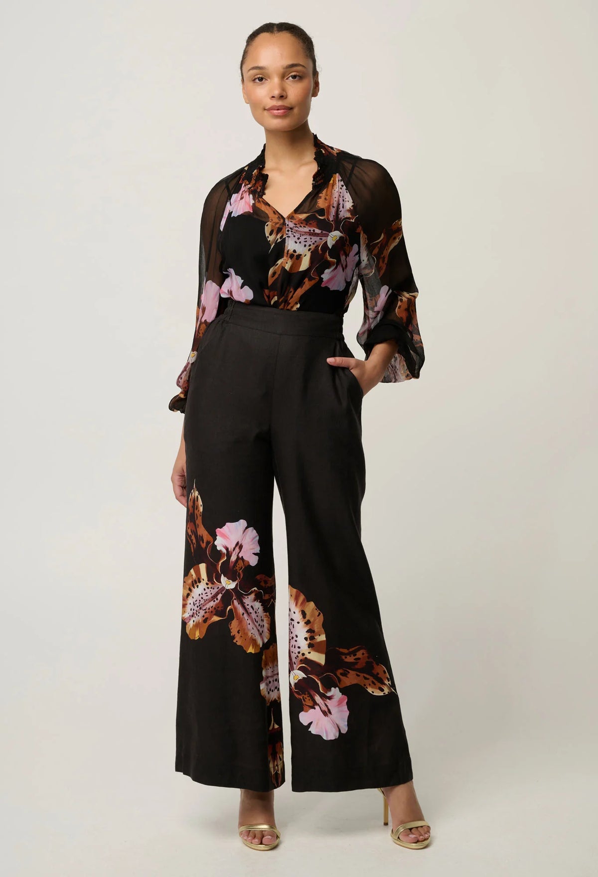 women wearing  a black blouse with floral design on a plain white background
