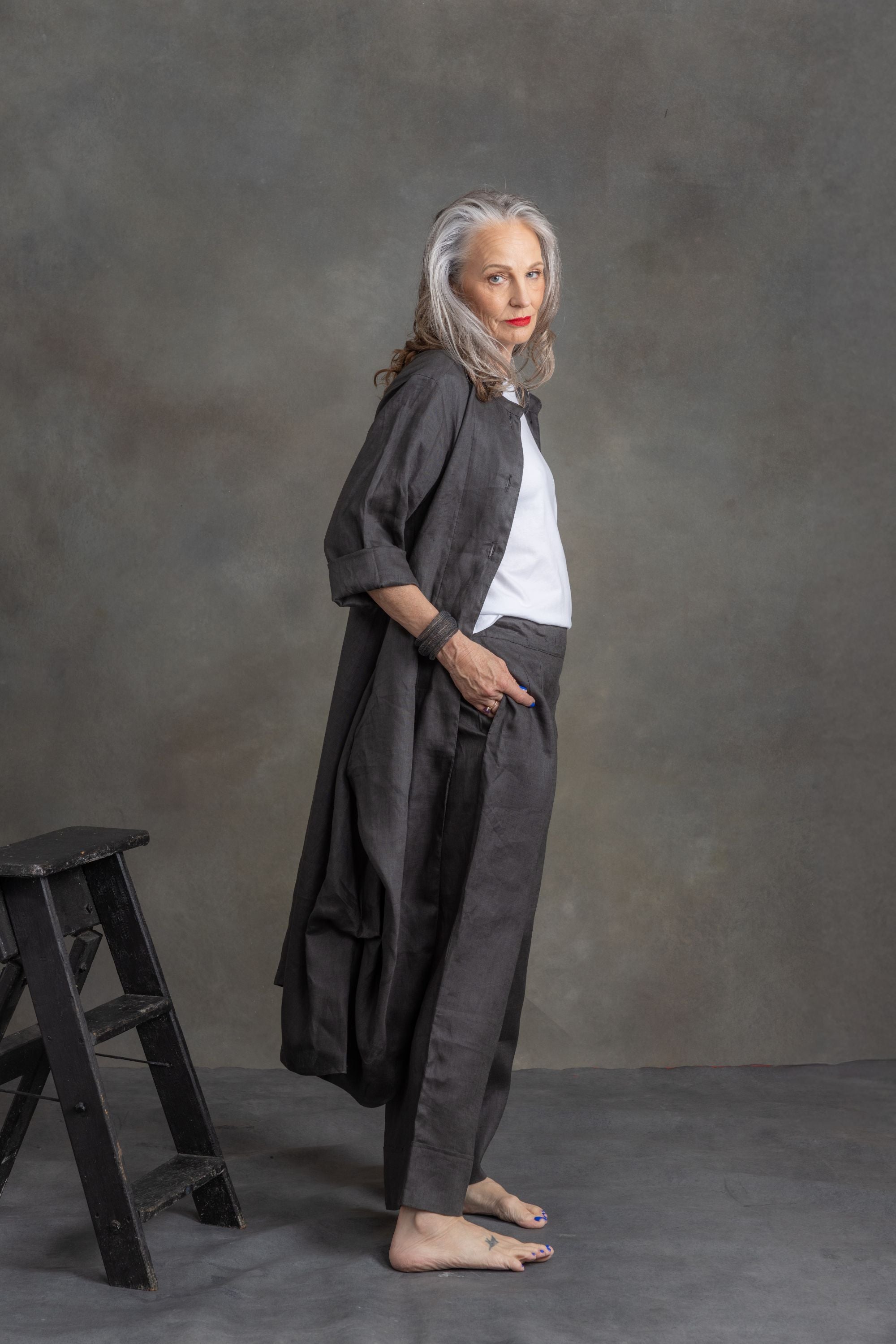 model wearing charcoal linen longline coat and matching pants in front of grey background