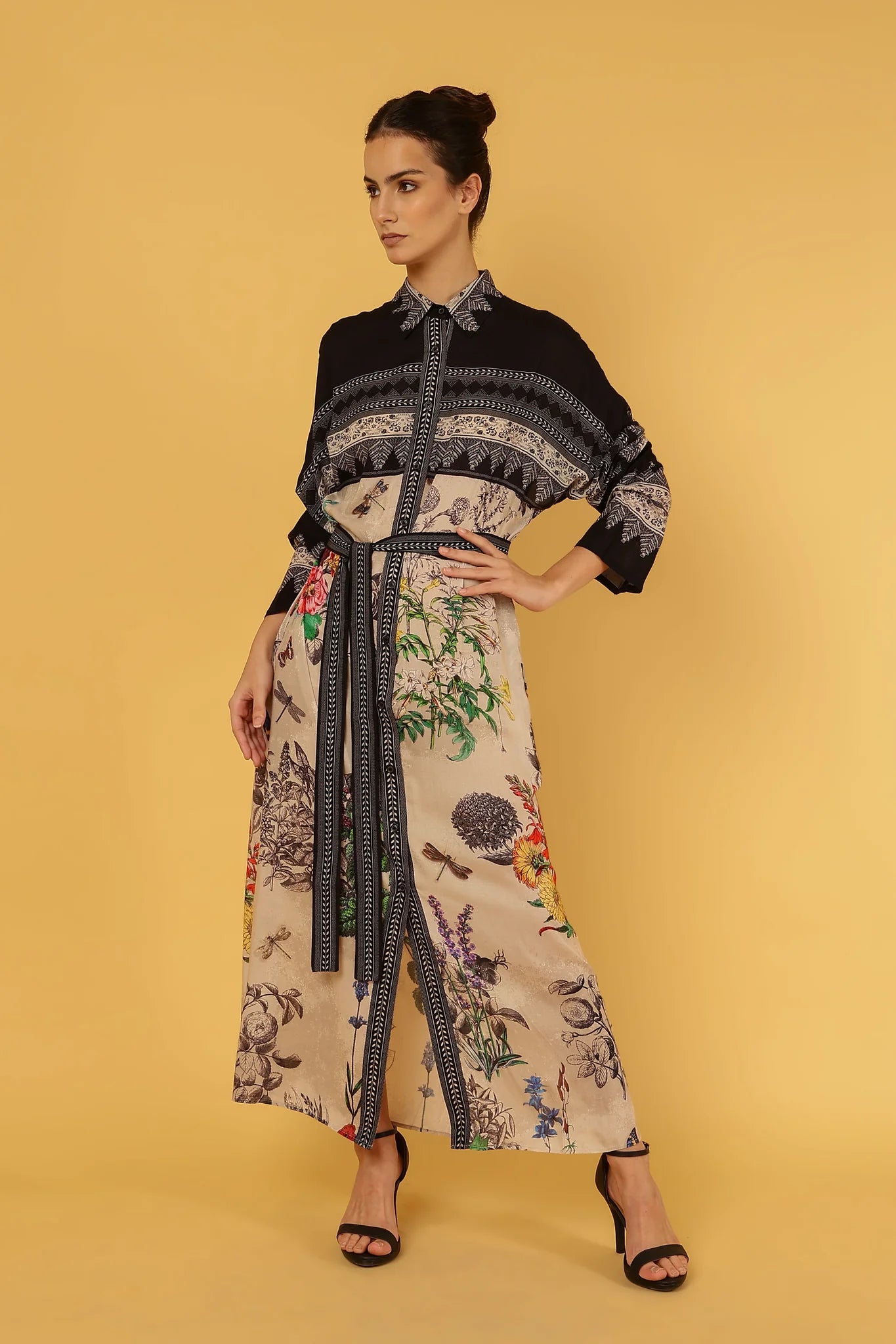 Woman wearing a floral dress with a black pattern on a yellow background