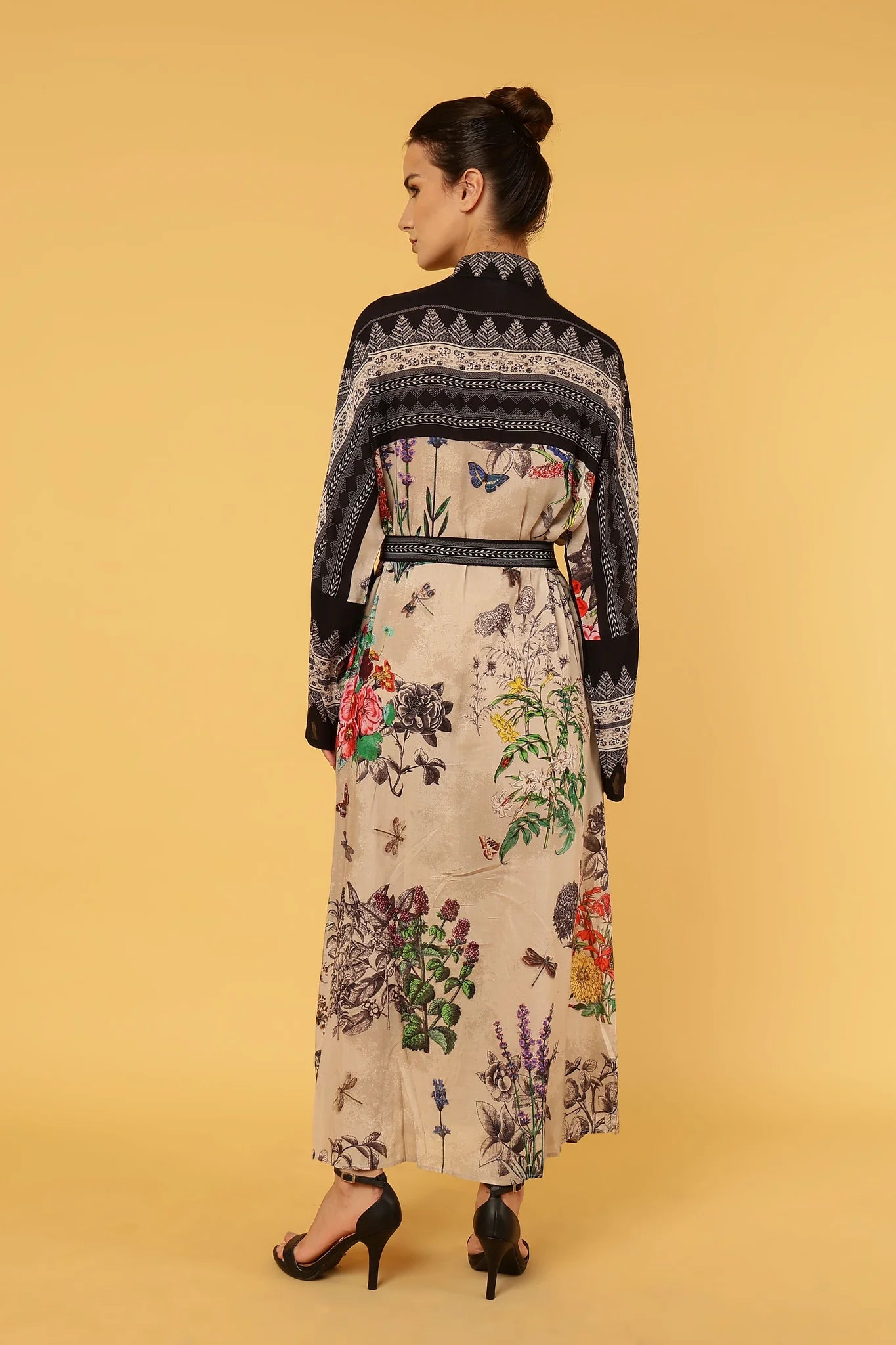 Woman wearing a floral dress with a black pattern on a yellow background