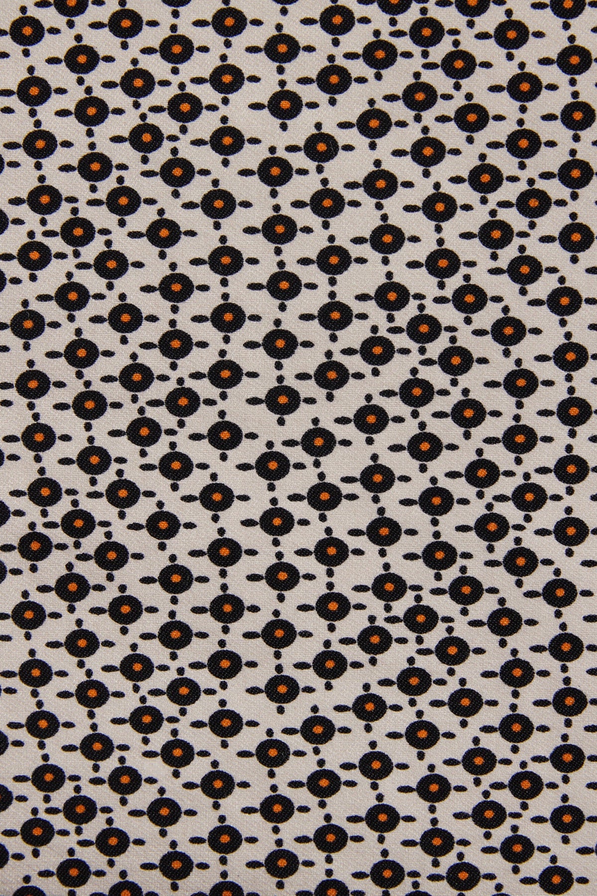 A close-up of a fabric pattern featuring a repeating geometric design of small black circles and dots on a light beige background, with some motifs highlighted in orange.