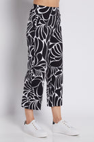 Black and white abstract patterned cropped pants worn by a model with white sneakers, photographed against a light gray studio background.
