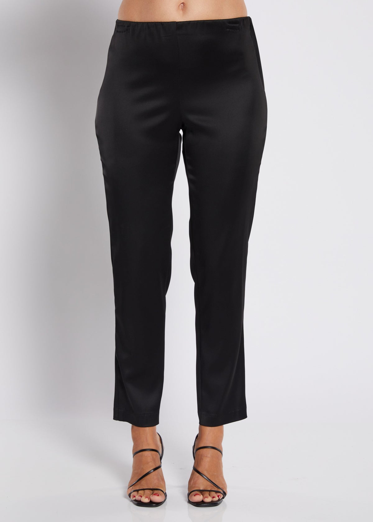 Black cropped pants shown on a model from the waist down, paired with black strappy high-heeled sandals against a light gray studio background.