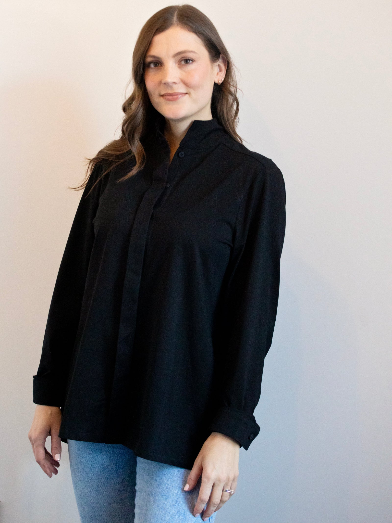 Woman wearing a black shirt and blue jeans against a plain background
