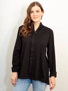 Woman wearing a black shirt and blue jeans against a white background