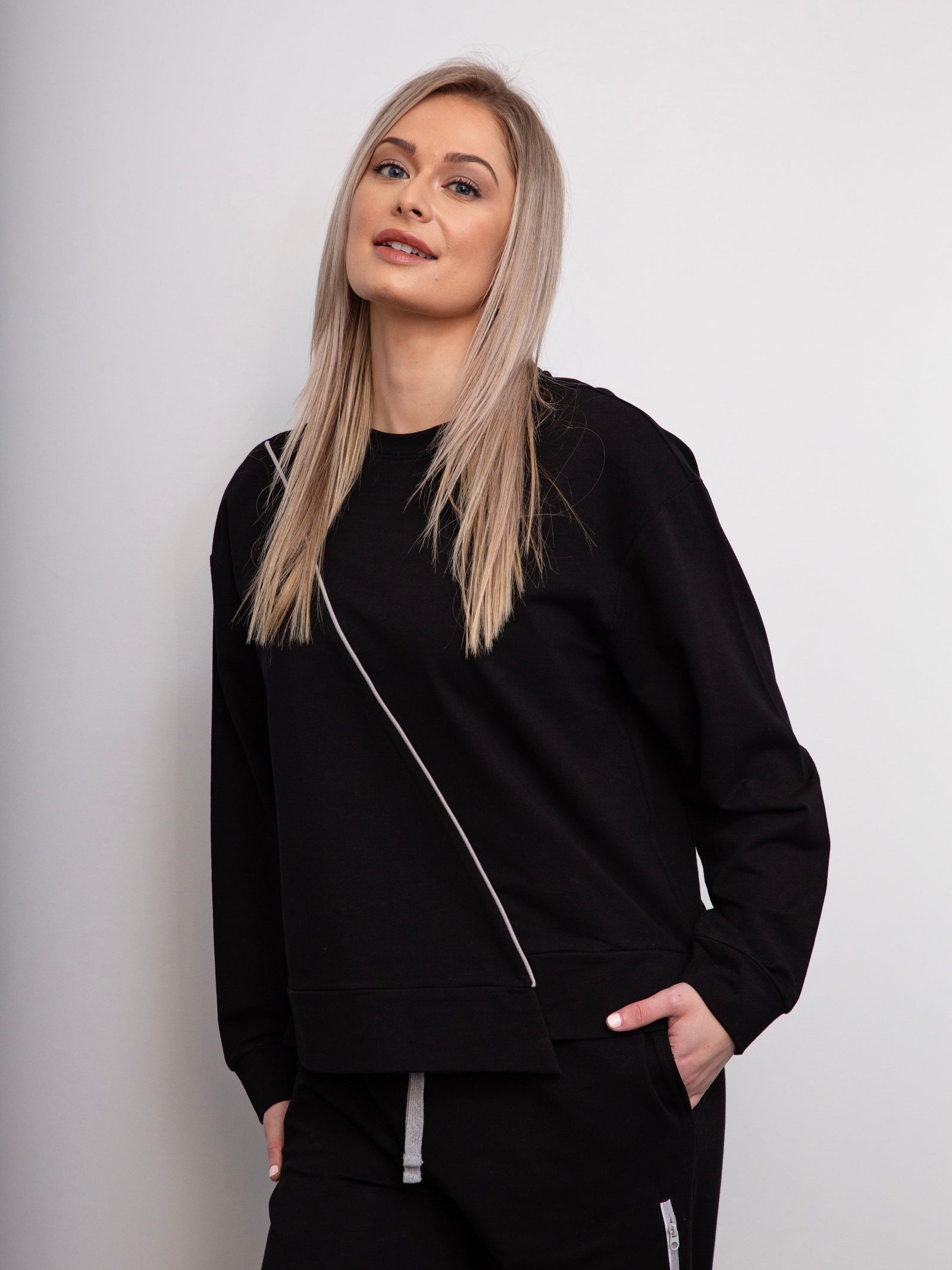 Woman wearing a black tracksuit against a plain background