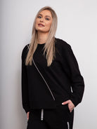 Woman wearing a black tracksuit against a plain background