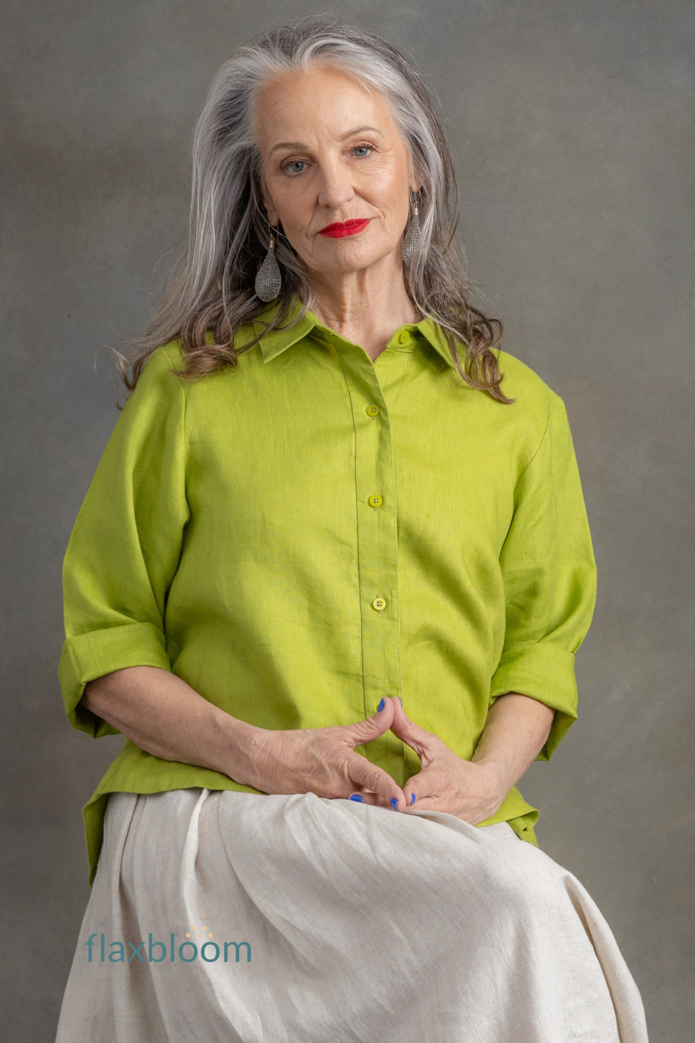 Woman wearing a green shirt and white pants against a gray background