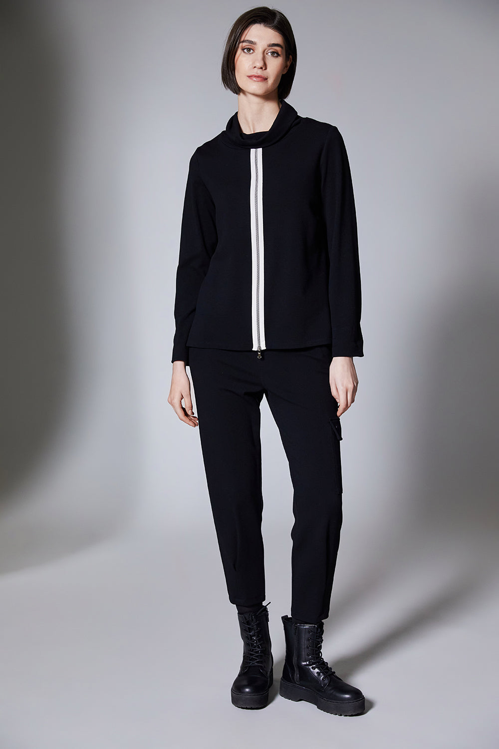 Person wearing a black outfit with a white stripe on a gray background