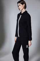 Person wearing a black tracksuit with white stripes on a gray background