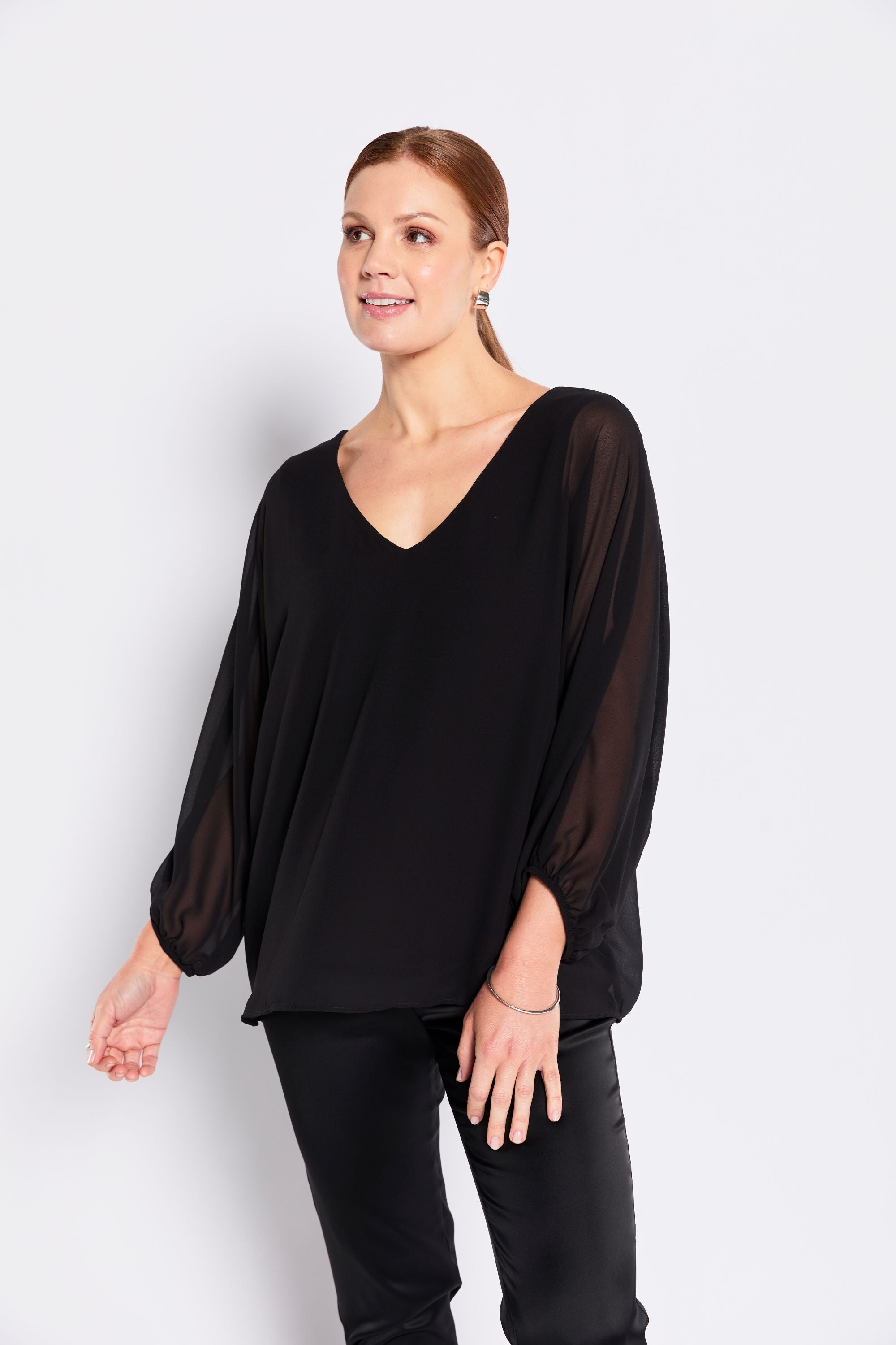 Woman wearing a black blouse and pants against a white background