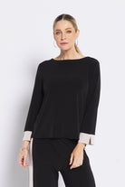 Woman wearing a black top with beige cuffs on a white background