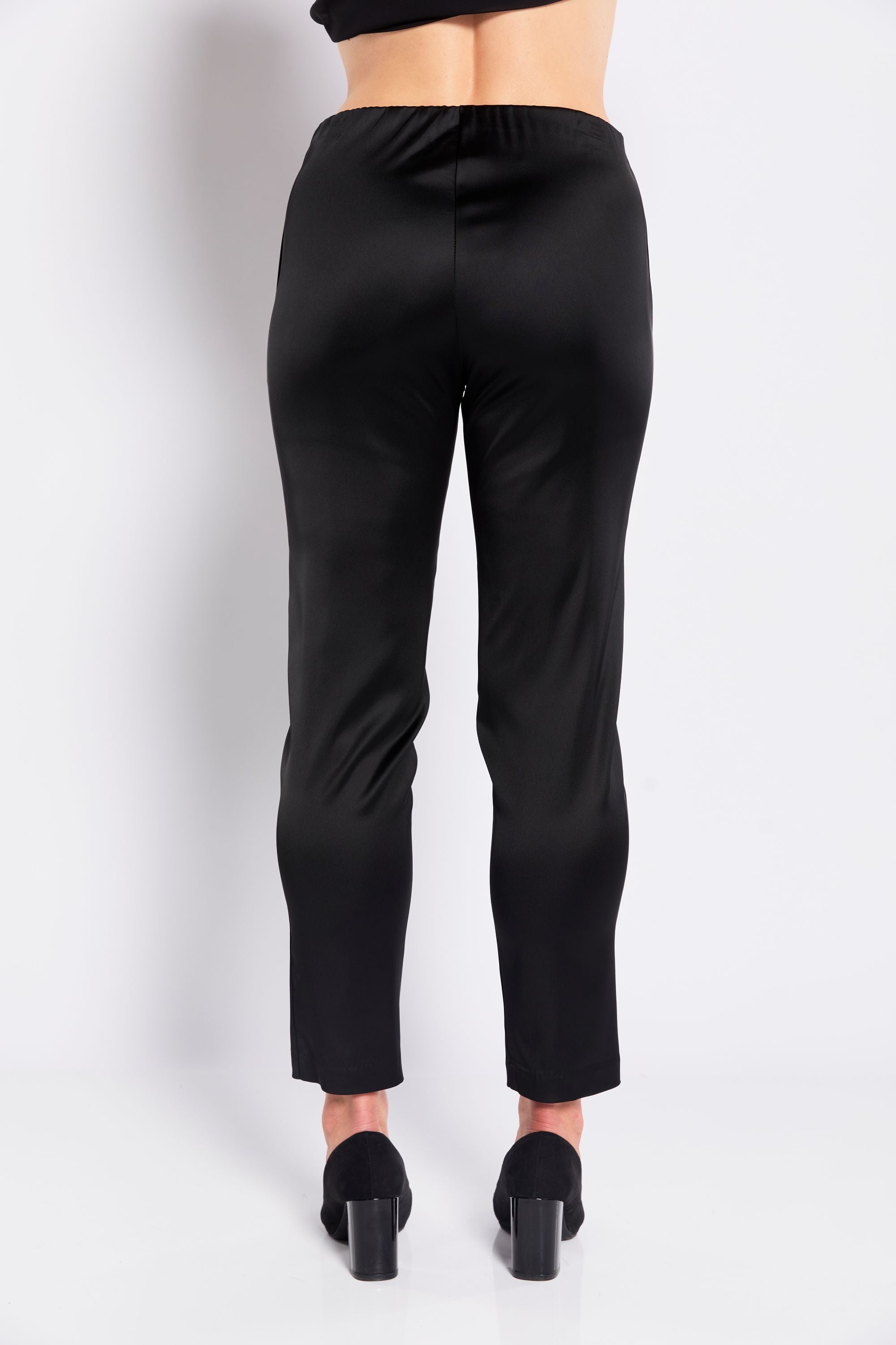 Black satin pants worn by a person on a white background back view