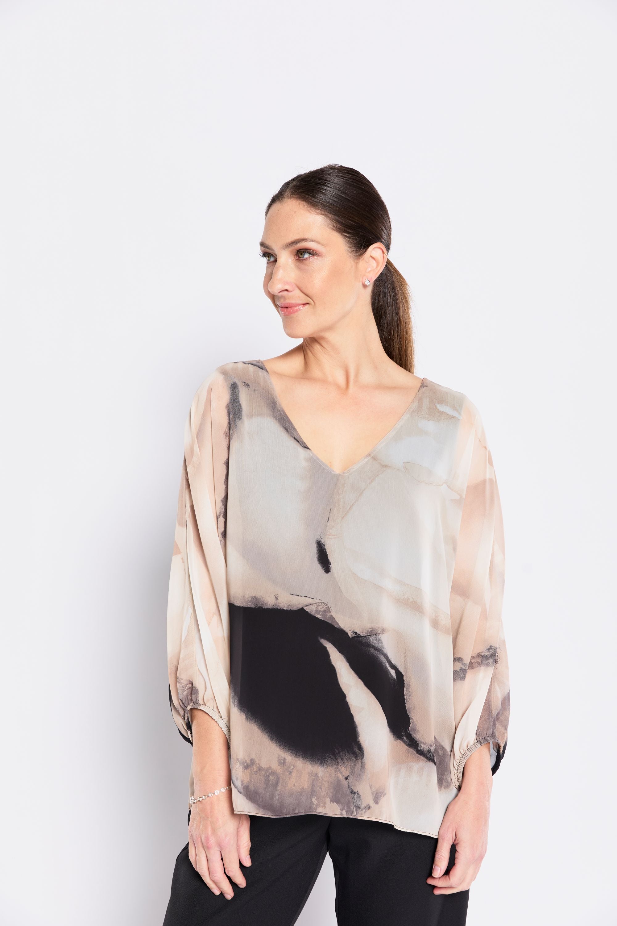 Woman wearing a sheer blouse with abstract design on a white background