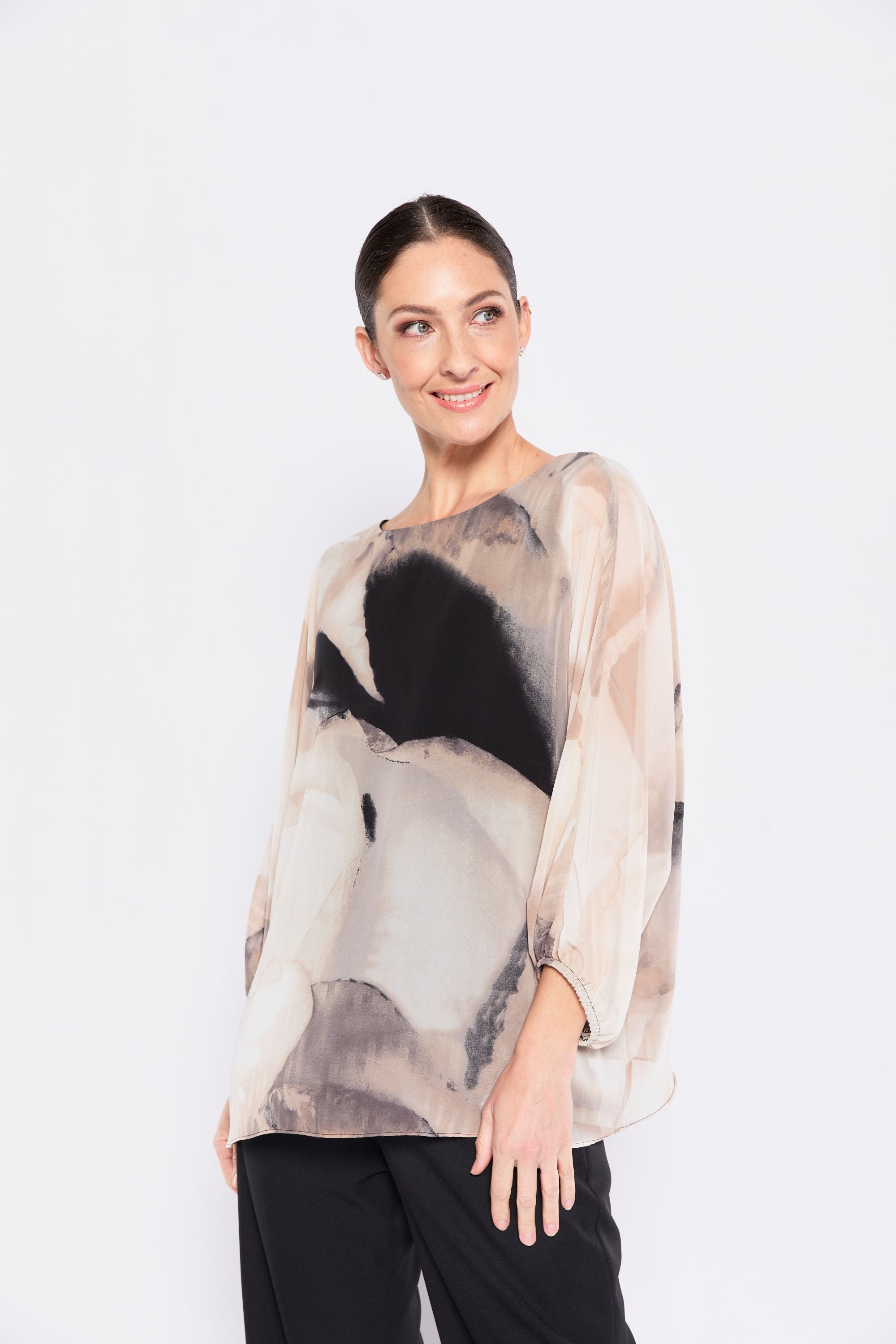 Woman wearing a sheer blouse with abstract design on a white background