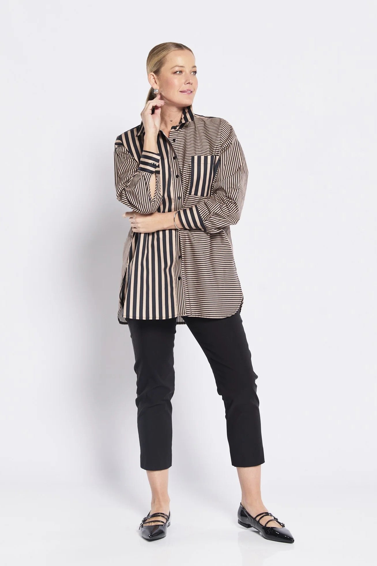 Woman wearing a striped shirt and black pants on a white background