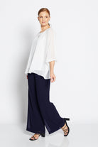 Woman wearing a white blouse and navy pants on a white background