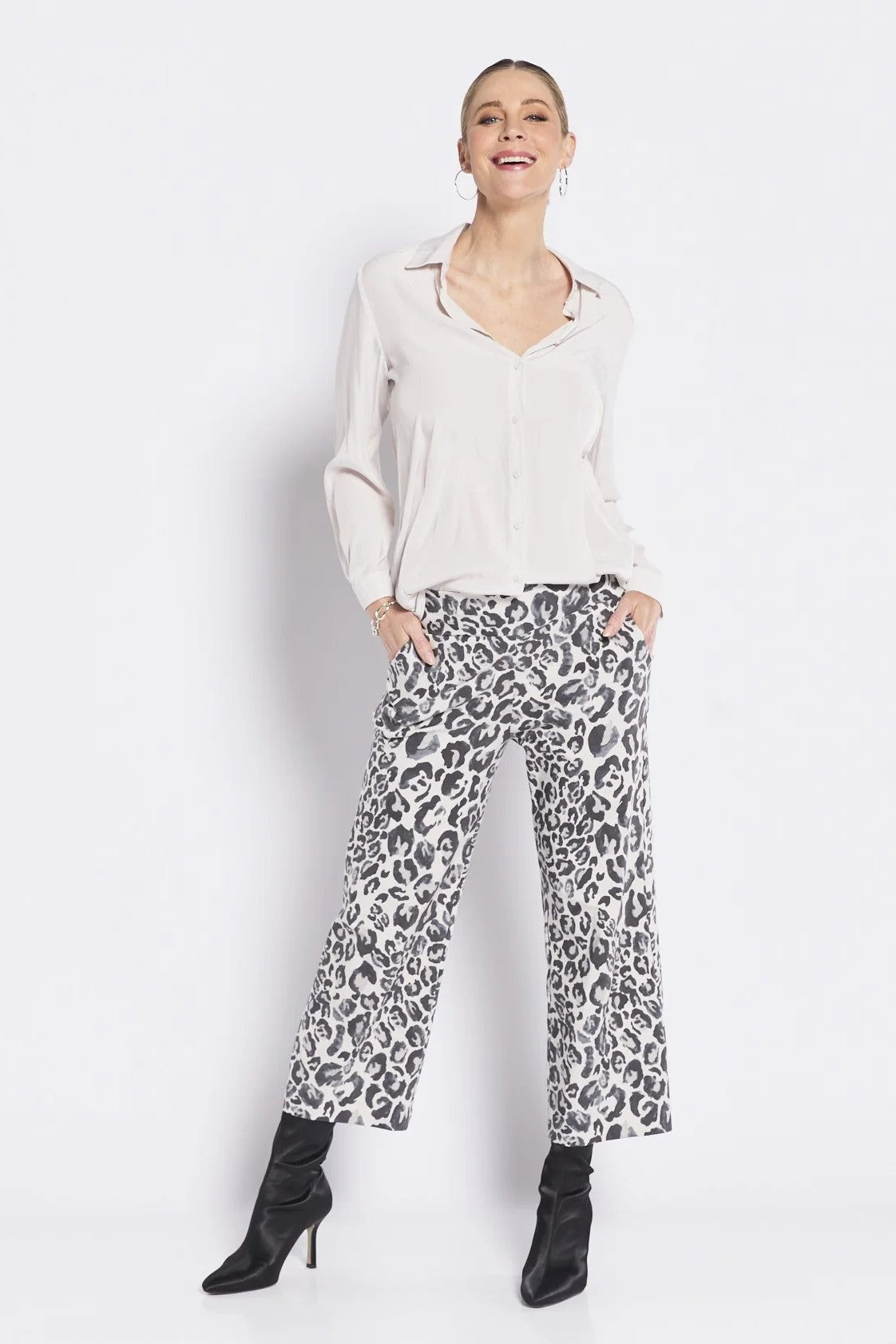 Woman wearing a white blouse and leopard print pants on a white background