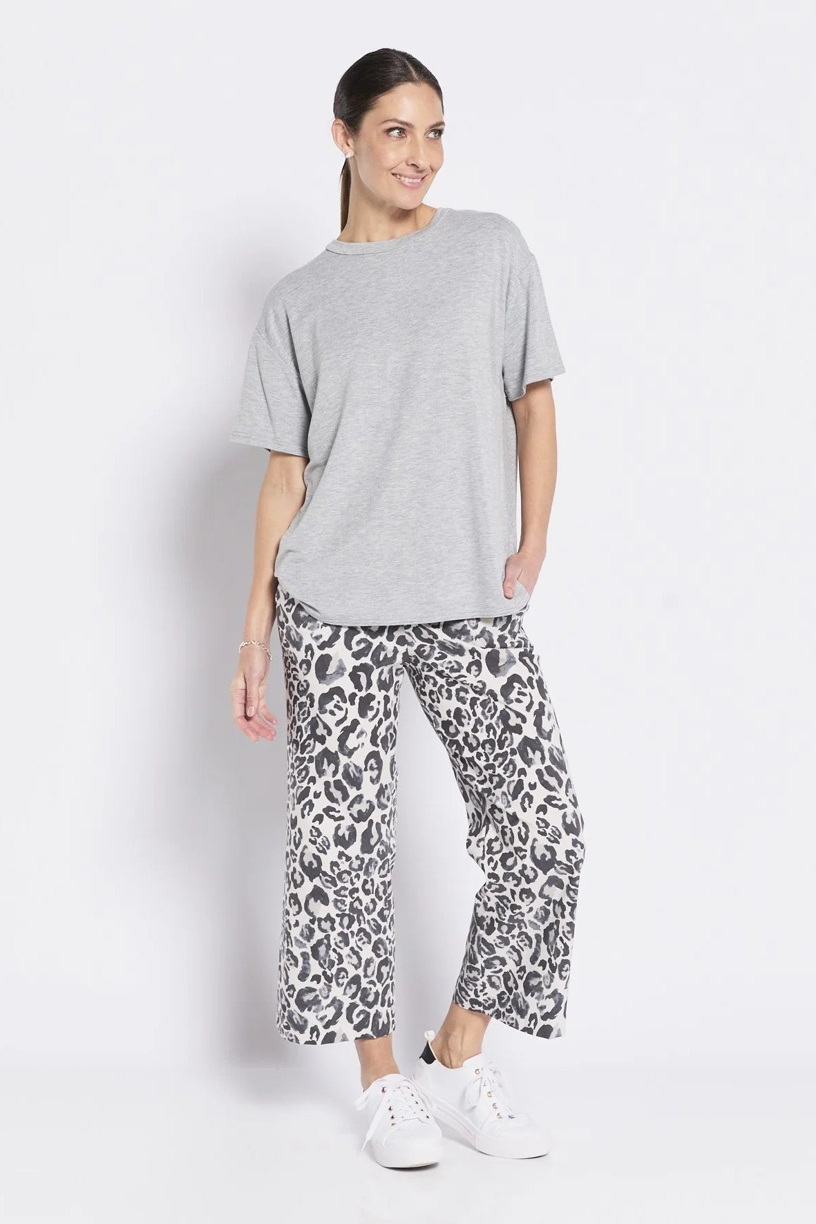 Woman wearing a gray t-shirt and leopard print pants on a white background
