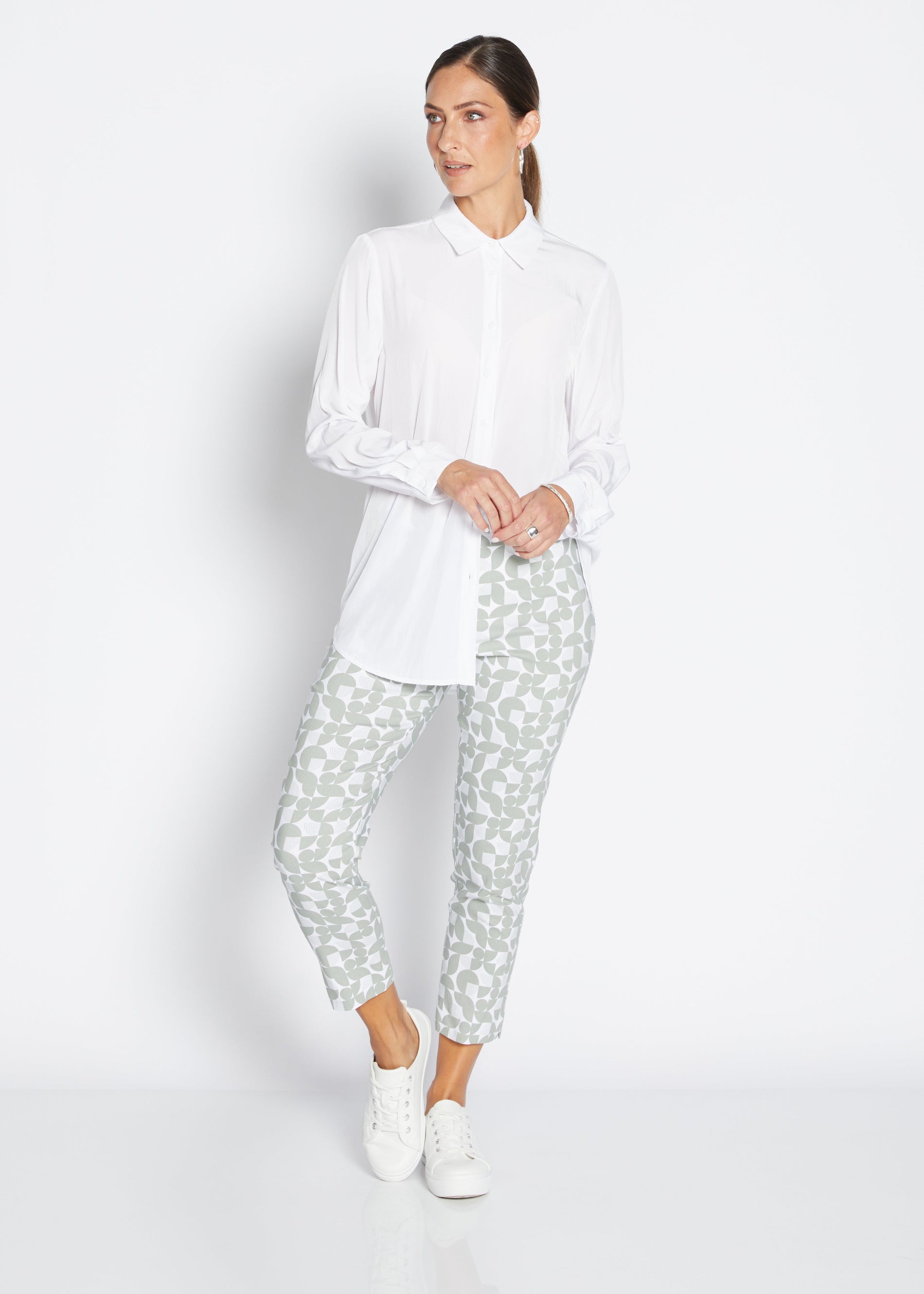 Woman wearing a white shirt and patterned pants on a white background