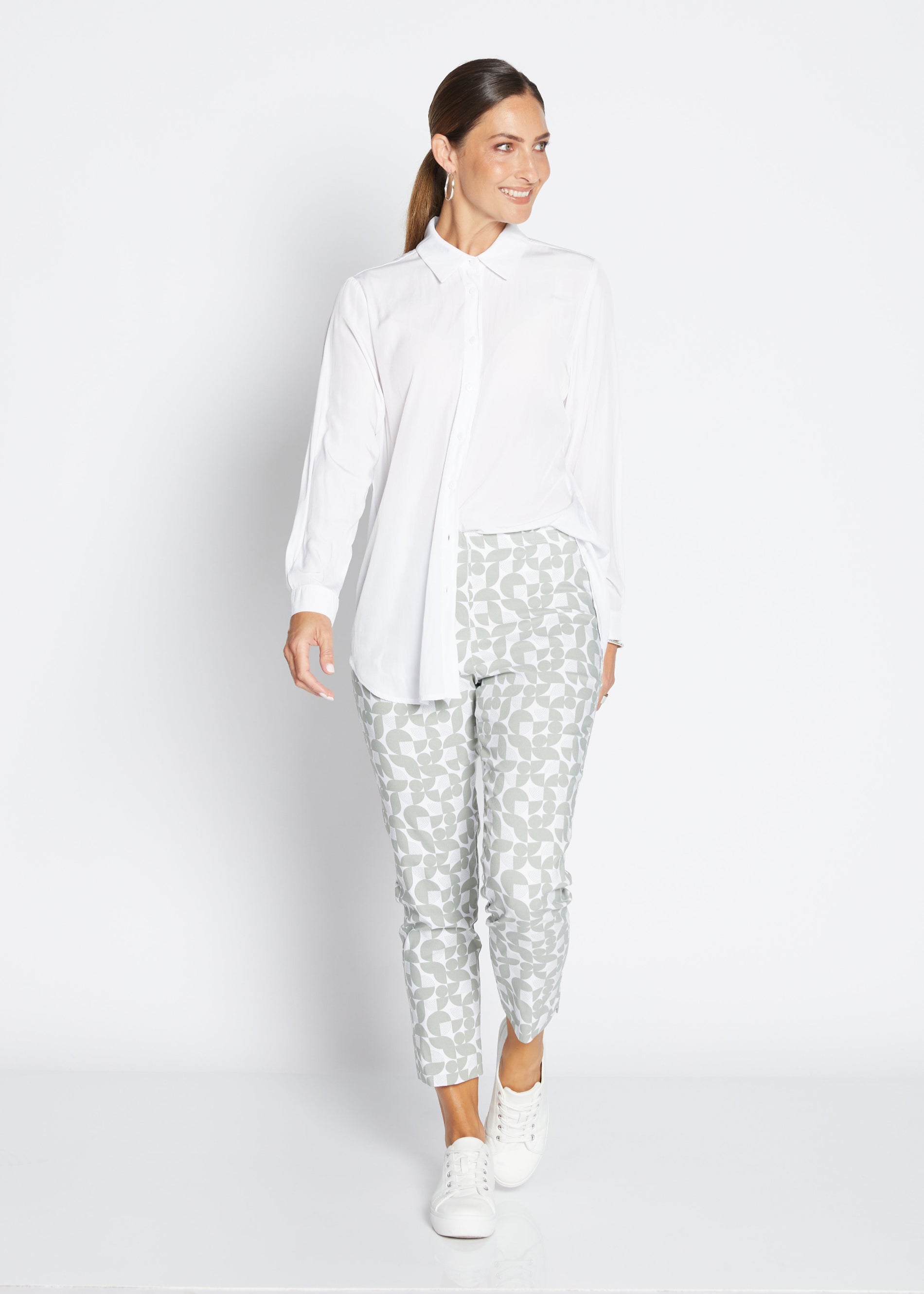 Woman wearing a white blouse and patterned pants on a white background