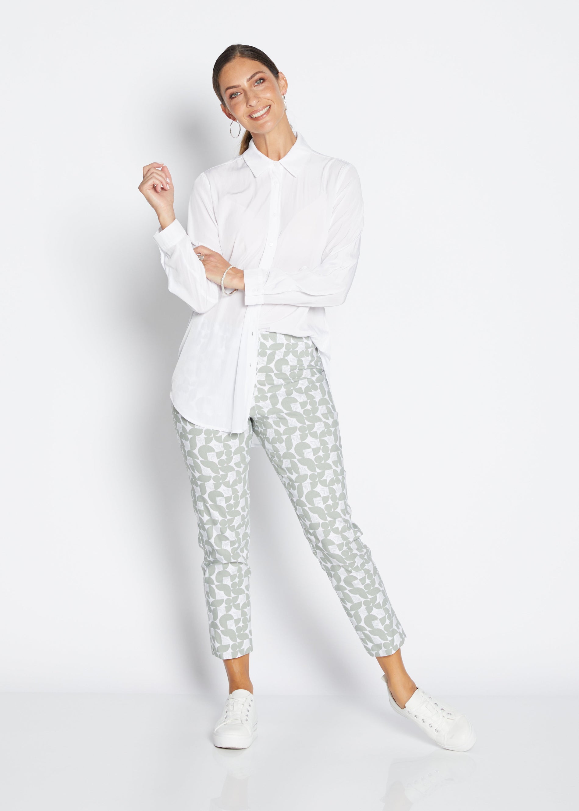 Woman wearing a white shirt and patterned pants on a white background