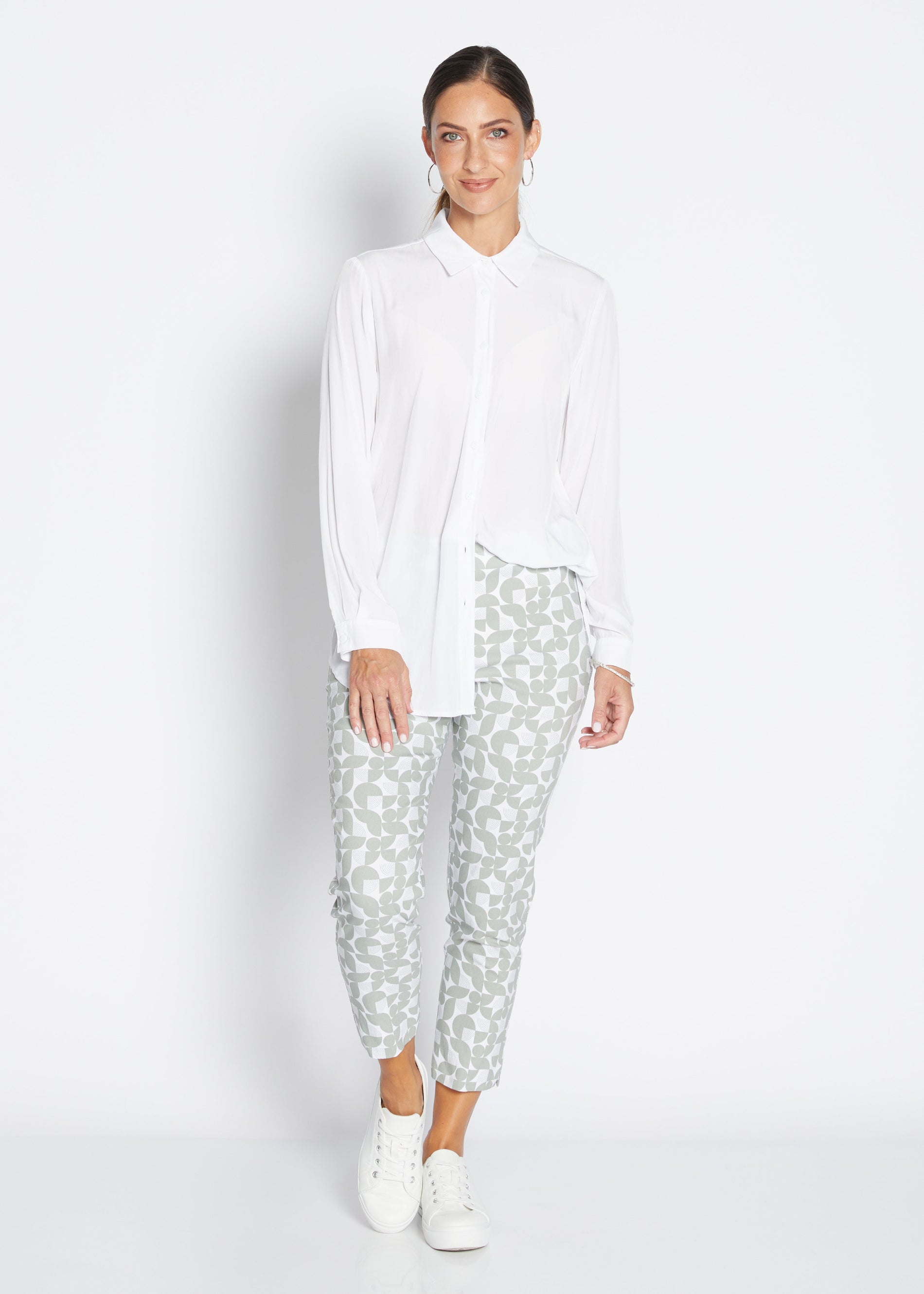 Woman wearing a white shirt and patterned pants on a white background