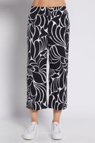 Black and white abstract floral print cropped pants worn by a model with white sneakers, photographed against a light gray studio background.