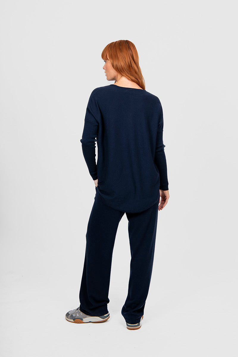 Person wearing a navy long-sleeve top and pants on a white background