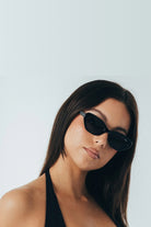 Woman wearing black sunglasses against a light gray background